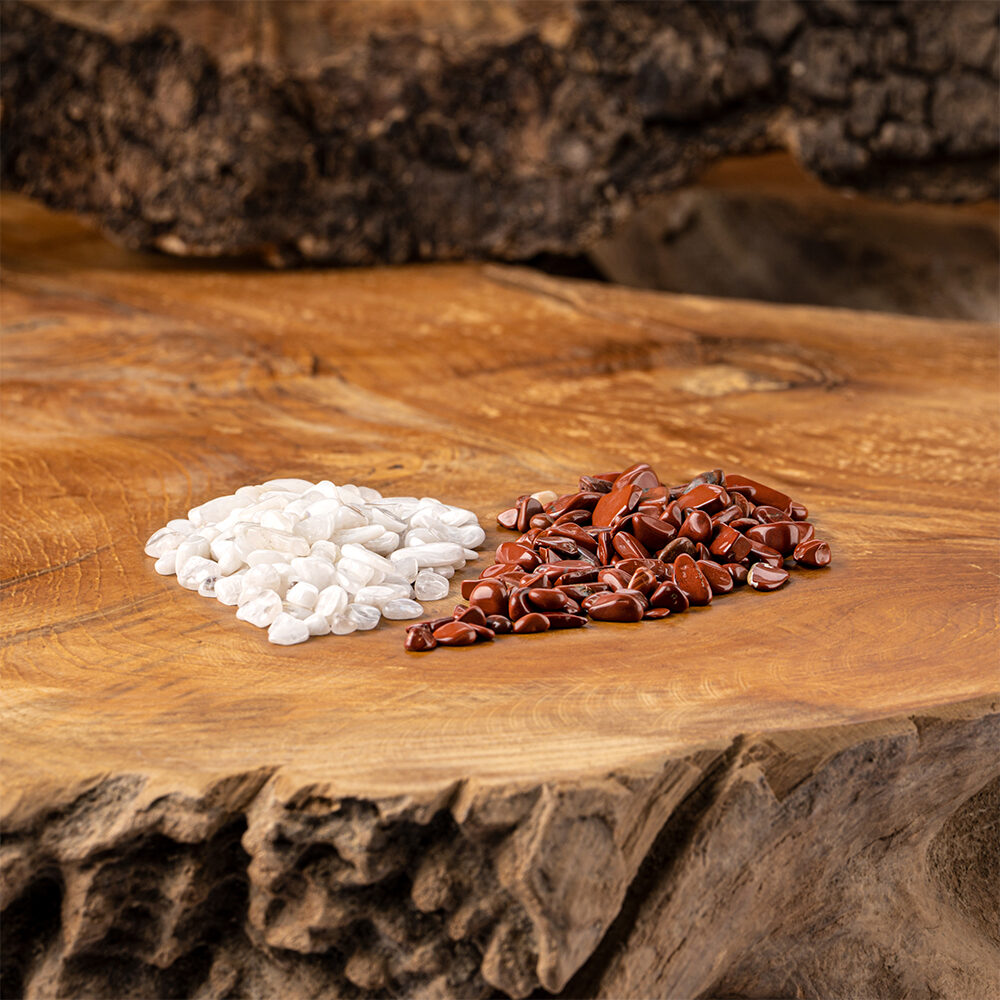 Zwei kleine Haufen mit Kristallsteinen, Roter Jaspis und Milchopal, liegen auf einer rustikalen Holzoberfläche.