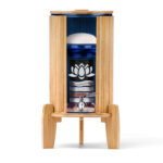 Ein Stand-Wasserfilter mit einem Gehäuse und Sockel aus Bambus, einem Behälter aus blauem Glas und einer Schnittansicht, die die inneren Filterstufen und Edelsteine zeigt.