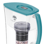 Detailansicht einer transparenten Wasserfilterkanne mit aquamarinblauem Deckel, die den mehrstufigen Filter und das Lotus Vita Logo zeigt.